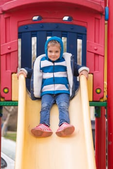 Cheerful little girl goes for a drive on a hill on a cool spring day