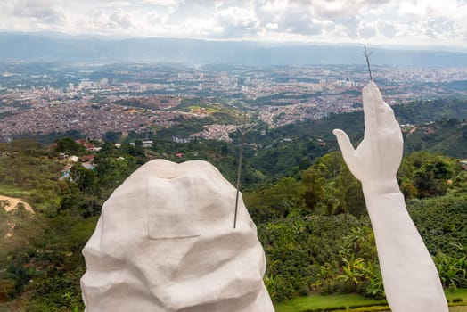 Head and hand of El Santisimo statue with Bucaramanga visible in the background