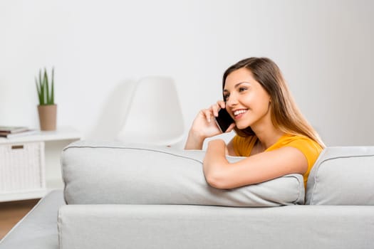 Top view of a beautiful young woman lying on a sofa and send text messages