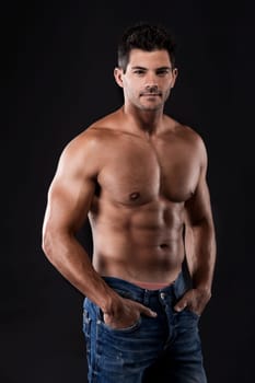 Portrait of a muscular man posing without a shirt against dark background