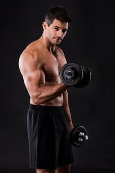 Portrait of a muscular man lifting weights against a dark background
