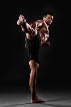 Portrait of a muscular man practicing body combat against a dark background