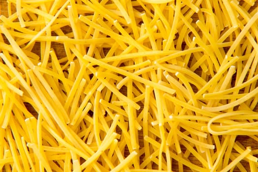 small dry pasta noodles on wood background or texture