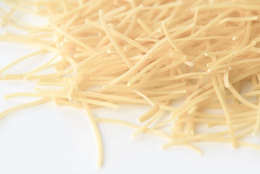 small dry pasta noodles on white background