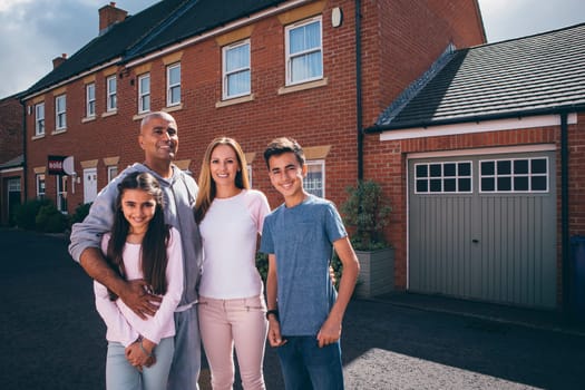 Happy family posing for the camera together outside of their home.