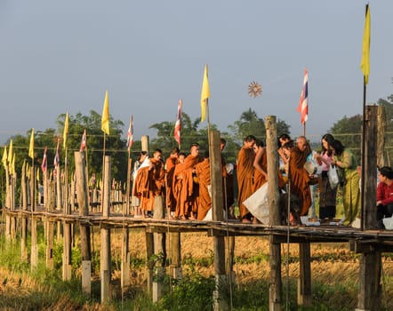 MAE HONG SON, THAILAND - NOVEMBER 21, 2015: Morning Buddhist Almsgiving at Zu Tong Pae bamboo bridge in Mae Hong Son, Thailand. Monks go on a daily almsround to collect food.