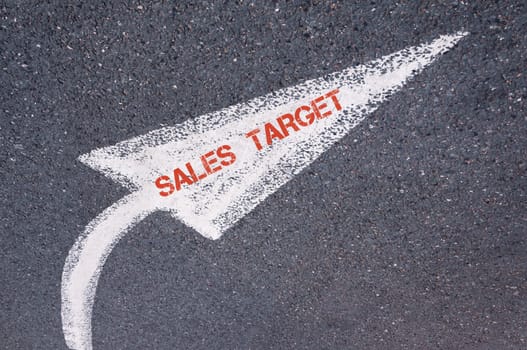 Directional white painted arrow with words SALES TARGET over road surface, concept image