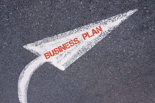 Directional white painted arrow with words BUSINESS PLAN over road surface, concept image