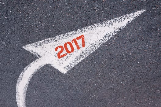 Directional white painted arrow with year 2017 over road surface, concept image