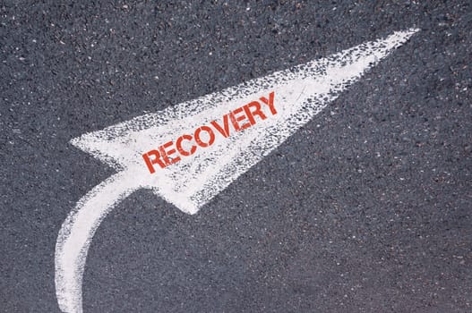Directional white painted arrow with word RECOVERY over road surface, concept image