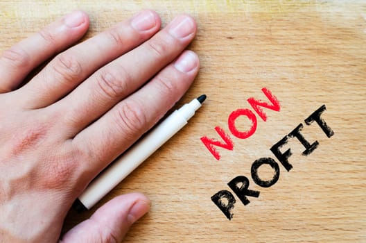 Human hand over wooden background and non profit text concept