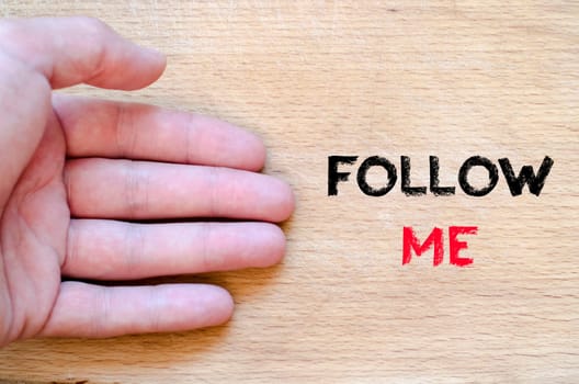 Human hand over wooden background and follow me text concept