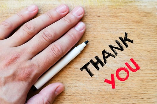 Human hand over wooden background and thank you text concept