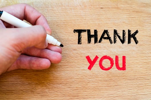 Human hand over wooden background and thank you text concept