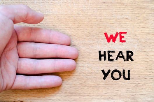Human hand over wooden background and we hear you text concept