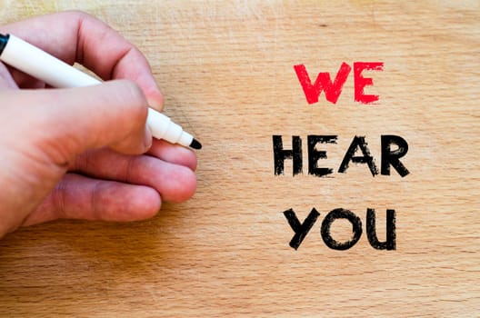 Human hand over wooden background and we hear you text concept