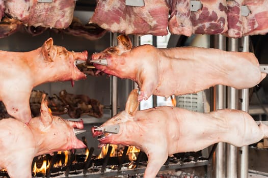 Carcasses of pork and other meat prepared on skewer. Cooking on grill and fire.