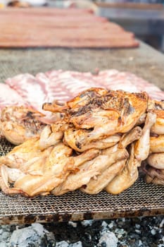 Inglese  Italiano.Chicken thighs cooked on the grill. During a village feast.