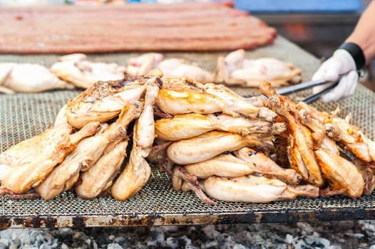 Inglese  Italiano.Chicken thighs cooked on the grill. During a village feast.