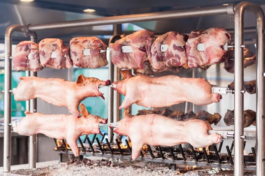 Carcasses of pork and other meat prepared on skewer. Cooking on grill and fire.