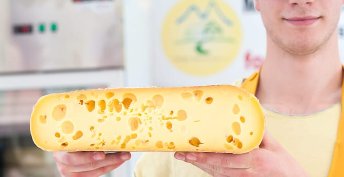 Alpine cheese for sale offered by a salesman.