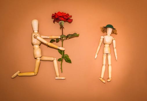 Red rose and figure wooden man and woman on brown background
