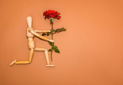 Red rose and figure wooden man on brown background