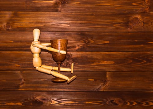 Wooden man with glass of wine on wooden background