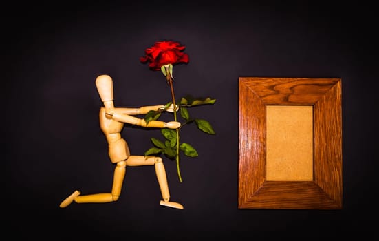 Red rose and figure wooden man on black background
