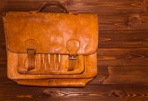 Old brown leather briefcase on wooden background