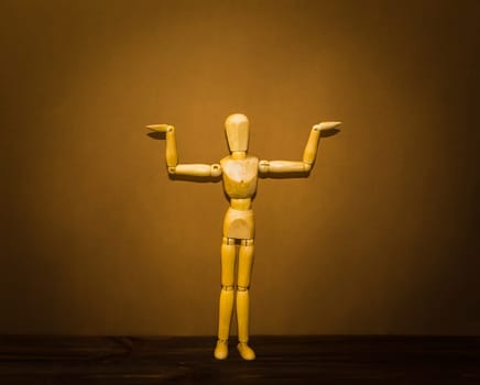 The wooden man with hands up to hold up your banner on brown background