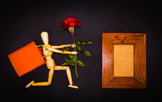 Red rose and figure wooden man on black background