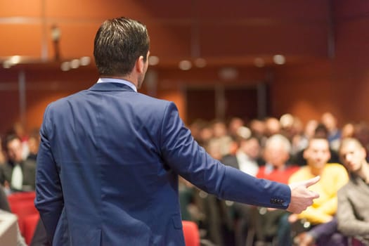 Speaker giving a talk on corporate Business Conference. Audience at the conference hall. Business and Entrepreneurship event.