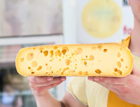 Alpine cheese for sale offered by a salesman.