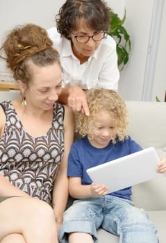 a child and his mother and his grandmother play with tablet
