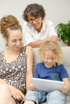 a child and his mother and his grandmother play with tablet