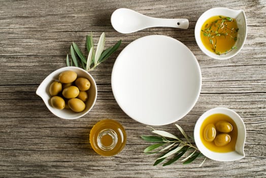 Olive oil with fresh herbs on wooden background
