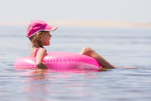 The girl in the cap swim in the river sat on the swimming circle