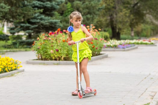 Girl riding a scooter down the avenue