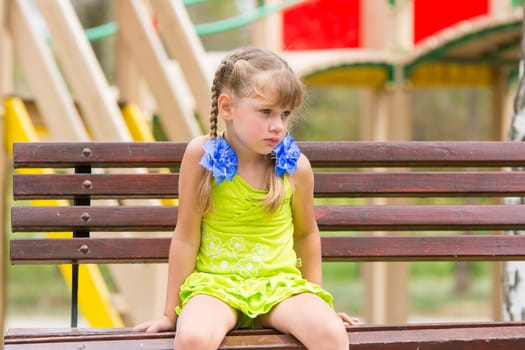 Offended five year old girl sitting on a bench and crying