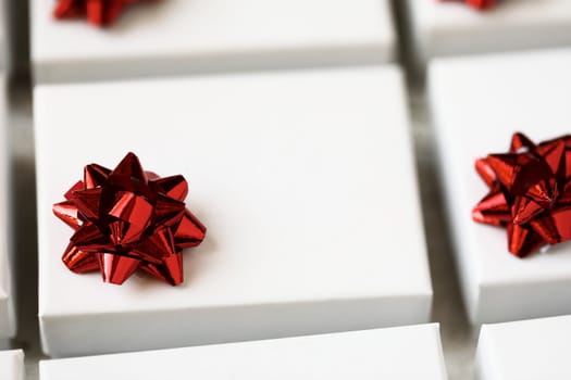 Close up of small white gift boxes with red bows.