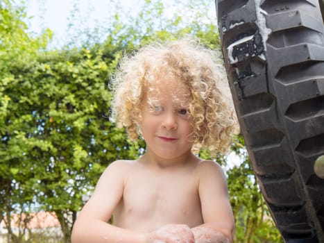little blond boy shirtless playing in the garden