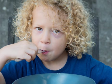 a little boy with blond curly hair, takes dinner