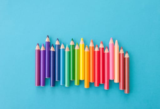 Colorful pencils in the gradient lined up on a blue background