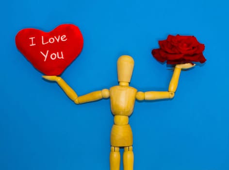 Red rose, heart and figure wooden man on blue background