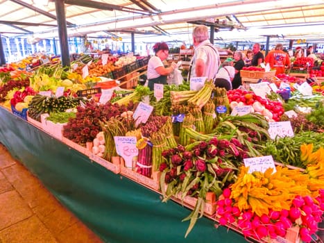 Venice, Italy - May 10, 2014: People near a counter with vegetables on a market in Venice, Italy
