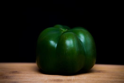close up on green paprika on wood,black background