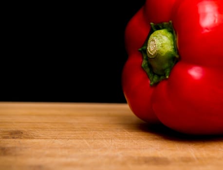 close up on red paprika on wood,black background