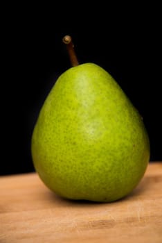 close up on pear on wood with black background