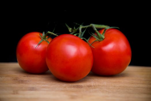 fresh cherry tomatoes on wood and black background